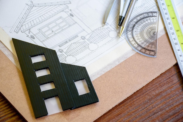 Plan projektowania architektonicznego domu z liniami lub szkicami i miniaturowym czarnym modelem budynku przy użyciu ołówka i narzędzi rysunkowych dla inżynierów