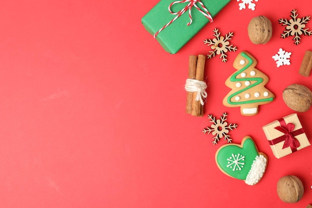 Zdjęcie płaska kompozycja z świątecznymi dekoracjami i smakołykami na czerwonym tle