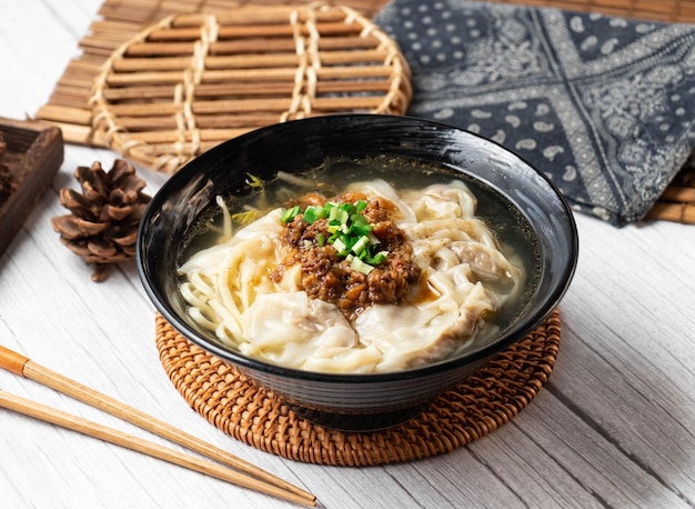Płaska zupa z makaronem w misce na białym tle na drewnianym stole widok z boku tajwan jedzenie