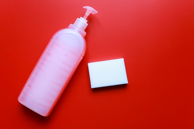 Płaski detergent do mycia naczyń i gąbka na czerwonym tle Czystość czyszczenia