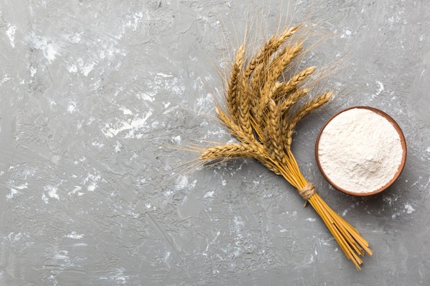 Płaski układ mąki pszennej w drewnianej misce z kłosami pszenicy na kolorowym tle światowy kryzys pszeniczny