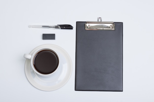 Płaskie, nowoczesne biurko z białym biurkiem, widok z góry. notatnik kawa, długopis i guma na białym tle