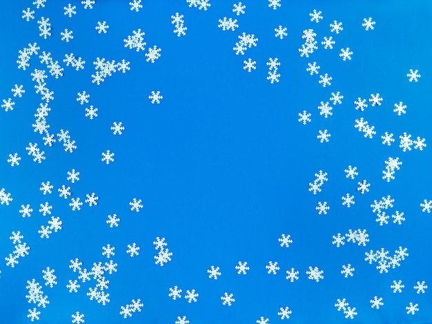 Płaskie układanie rozproszonych białych płatków śniegu na niebiesko