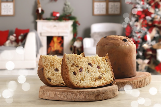 Zdjęcie plasterek panettone z kandyzowanymi owocami w domu z dekoracją świąteczną w tle.