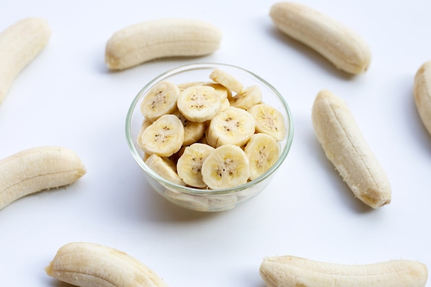 Plasterki banana w szklanej misce na białym tle.
