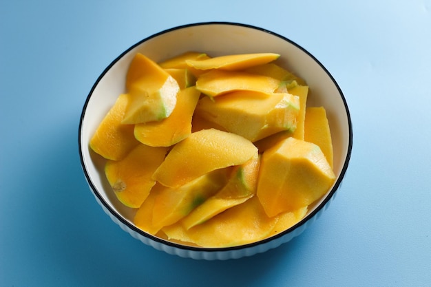 Zdjęcie plasterki mango na białym talerzu sałatkowym na jasnoniebieskim tle