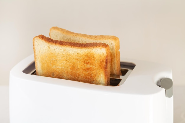 Plasterki pieczonego chleba tostowego w nowoczesnym tosterze na stole kuchennym