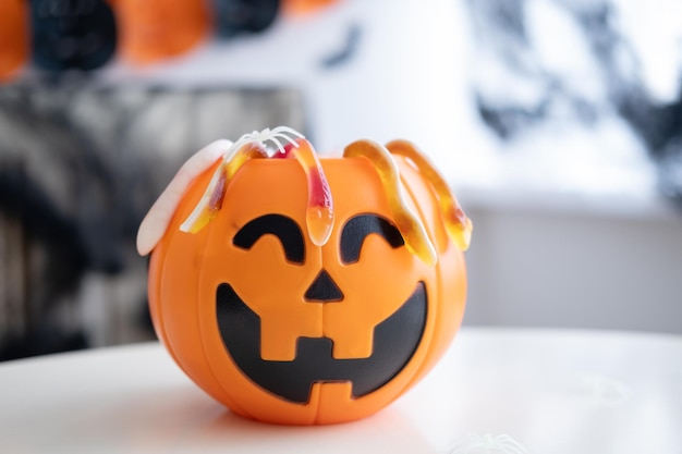 Plastikowa latarnia jack o z marmoladą na białym stole na tle ozdobionym halloween