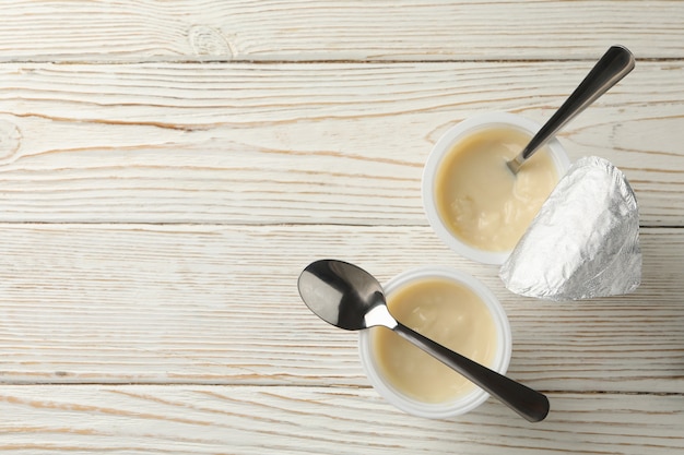 Plastikowe kubki jogurtu i łyżki na białym tle drewnianych