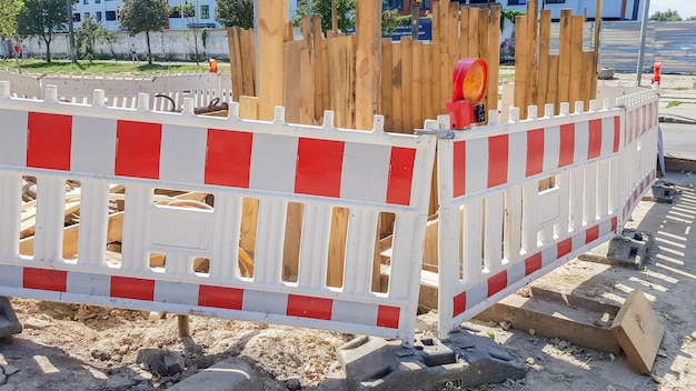 Zdjęcie plastikowe ogrodzenia barierowe na terenie robót drogowych. czerwony i biały plastikowy płot w pobliżu miejsca naprawy ulicy. roboty budowlane na ulicy, remont drogi, ogrodzenie ochronne.