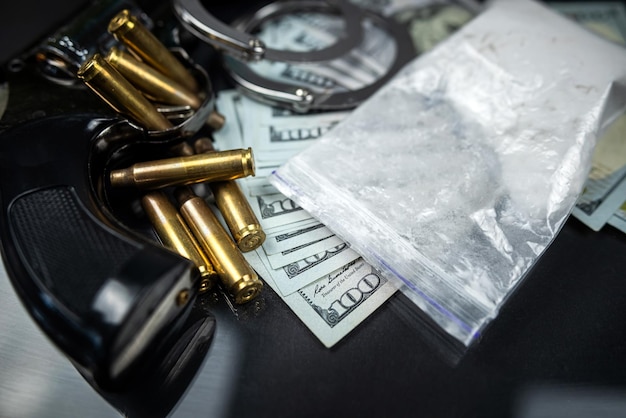Plastikowe torby kokainy lub heroiny i banknoty dolarowe z kajdankami i kulami z pistoletu