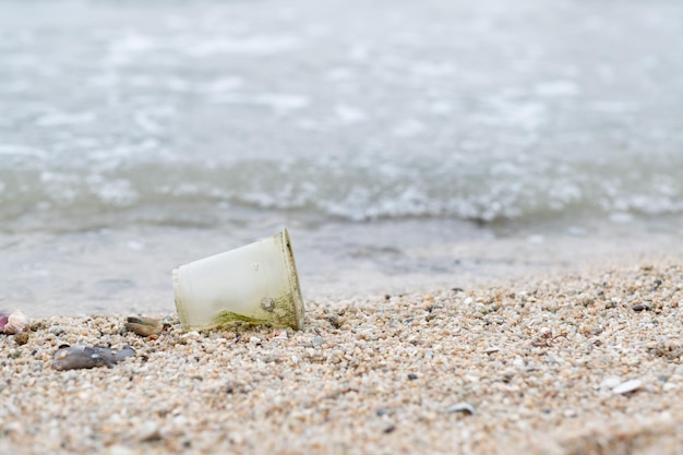 Plastikowy kubek na plaży brudne morze