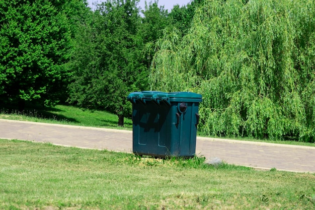 Plastikowy pojemnik na śmieci w parku miejskim w słoneczny letni dzień