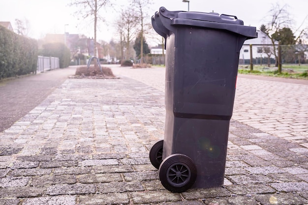 Plastikowy śmietnik stoi na poboczu drogi i czeka na śmieciarkę na wsi