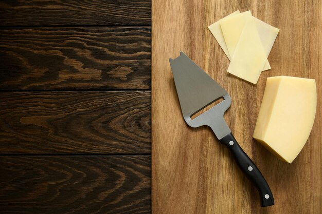 Plastry parmezanu w plasterkach na drewnianej desce specjalnym nożem