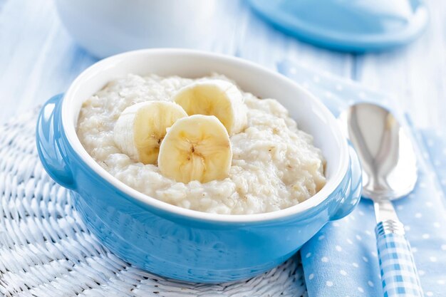 Zdjęcie płatki owsiane z plasterkami banana w niebieskiej misce