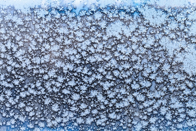 Płatki śniegu i wzór szronu na zamarzniętej szybie