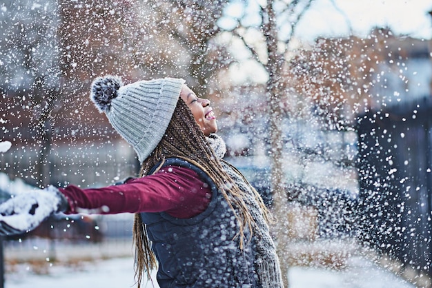 Płatki śniegu jak pocałunki z nieba Ujęcie szczęśliwej młodej kobiety rzucającej śnieg w zimowy dzień na świeżym powietrzu