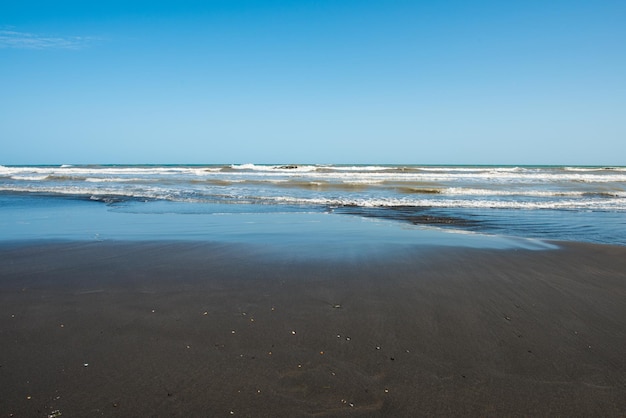 Plaża z błękitnym niebem i oceanem w tle.