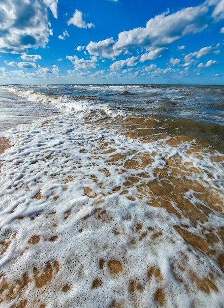 Plaża z falami, a niebo jest niebiesko-białe.