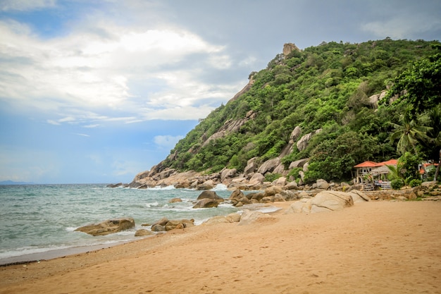 Plaża z górami, niebieskim niebem i kamieniami nad morzem