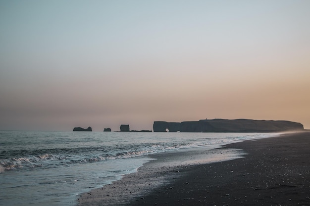 Plaża z różowym niebem i małą wyspą w oddali