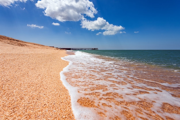 Plaża z turkusowym morzem i żółtym piaskiem, kurort lato w tle