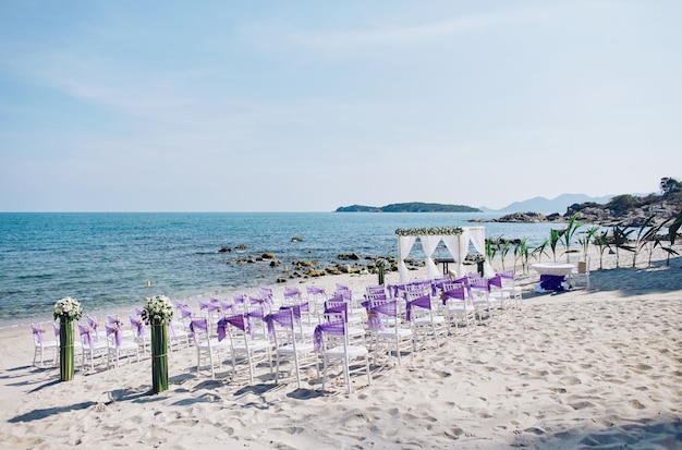 Plażowi ślub miejsca wydarzenia położenia z białymi chiavari krzeseł dekoracją z purpurowym organza sas