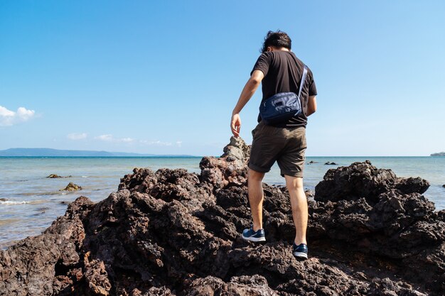 Plecy mężczyzna chodzi nad morze kamieniem przy Koh Mak wyspą w Tracie, Tajlandia