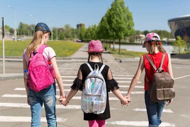 Zdjęcie plecy uczniów z kolorowymi plecakami poruszającymi się po ulicy