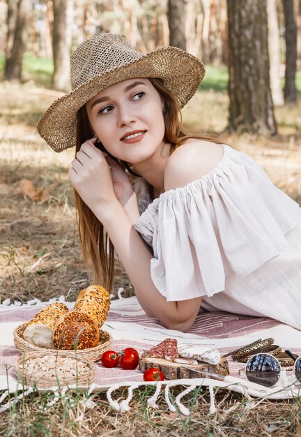 pled na którym leży piknik, kiełbaski, orzechy, czerwone pomidory i świeże bułeczki.