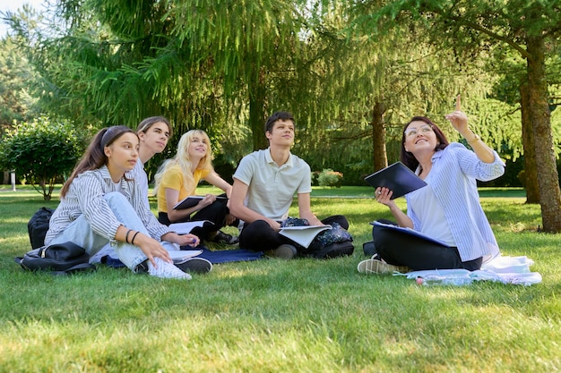 Plenerowa grupa studentów z nauczycielką siedzącą na trawie