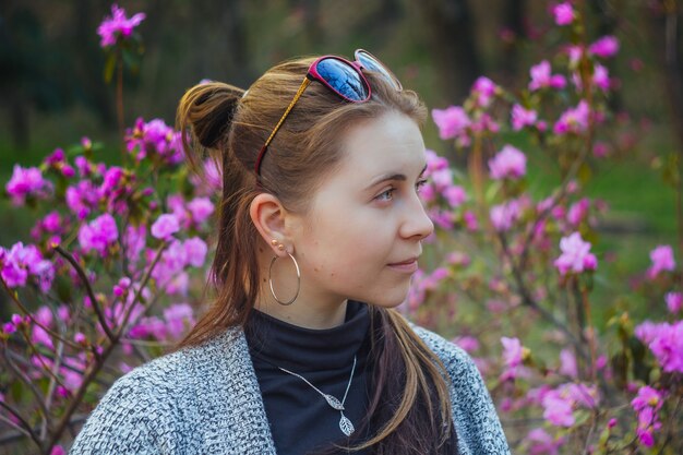 Plenerowy portret europejska kobieta w krzaku różowi i purpurowi kwiaty w parku