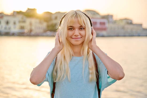 Plenerowy portret szczęśliwej młodej blondynki w słuchawkach