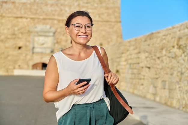 Plenerowy portret uśmiechniętej kobiety w średnim wieku chodzącej po starym mieście