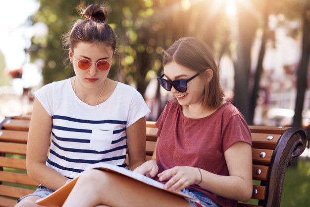 Plenerowy strzał dwa żeńskiego przyjaciela jest ubranym okulary przeciwsłonecznych