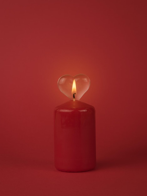 Płomień płonącej świecy na tle szklanego serca. Pojęcie romantycznego związku.
