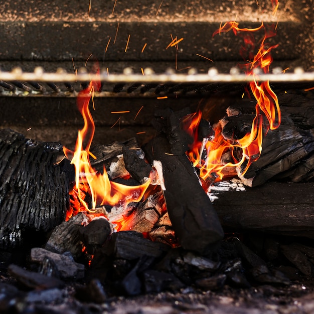 Płonące czerwone gorące iskry od płonącego węgla w grillu