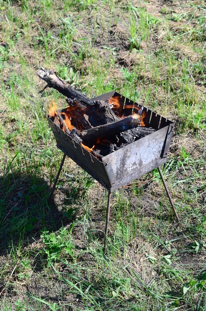 Zdjęcie płonące drewno wewnątrz grilla na leśnym polu na świeżym powietrzu