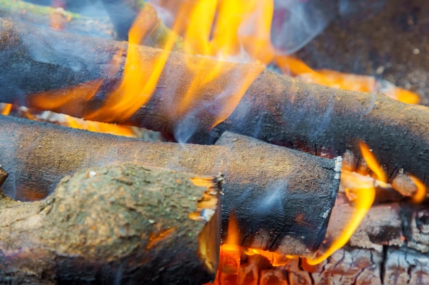 Płonący na tablicy ogniowej Ognisko z płomieniem dymi drewniane deski i węgle drzewne Zbliżenie zdjęcia z selektywną ostrością i rozmytym tłem
