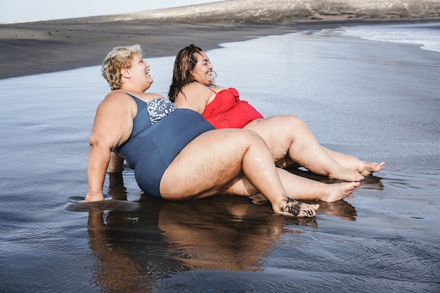 Plus size kobiety siedzą na plaży i bawią się podczas letnich wakacji