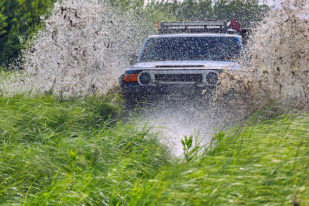Plusk wody w wyścigowym SUV-ie terenowym jadącym przez niebezpieczną barierę wodną