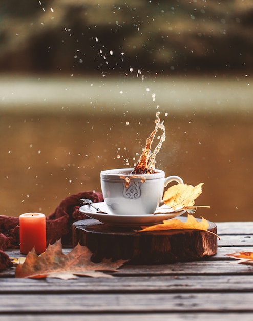 Pluśnięcie kawy na zewnątrz. Jesienna kompozycja na zewnątrz. Jesień. Filiżanka gorącej kawy na zewnątrz.