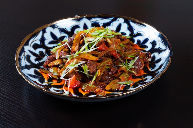 Płyta z siekanym mięsem i warzywami na czarnym tle Kuchnia azjatycka