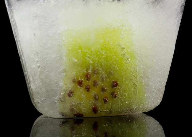 Płytka owocu kiwi zamrożonego w lodzie na czarnym tle
