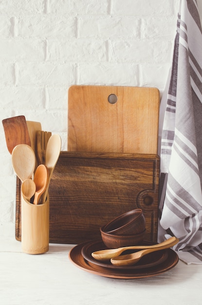 Płytki ceramiczne, sztućce drewniane lub bambusowe, deski do krojenia i ręcznik we wnętrzu kuchni.