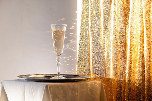 Płytki szampana w tacce na stole na złotym błyszczącym tle