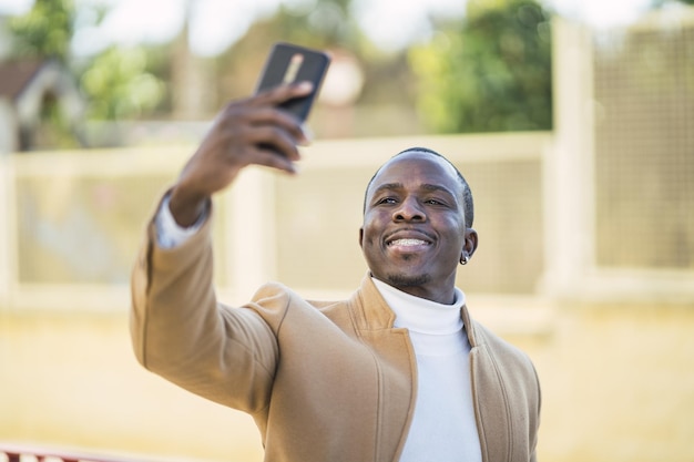 Płytkie ujęcie przystojnego afrykańskiego mężczyzny robiącego selfie smartfonem
