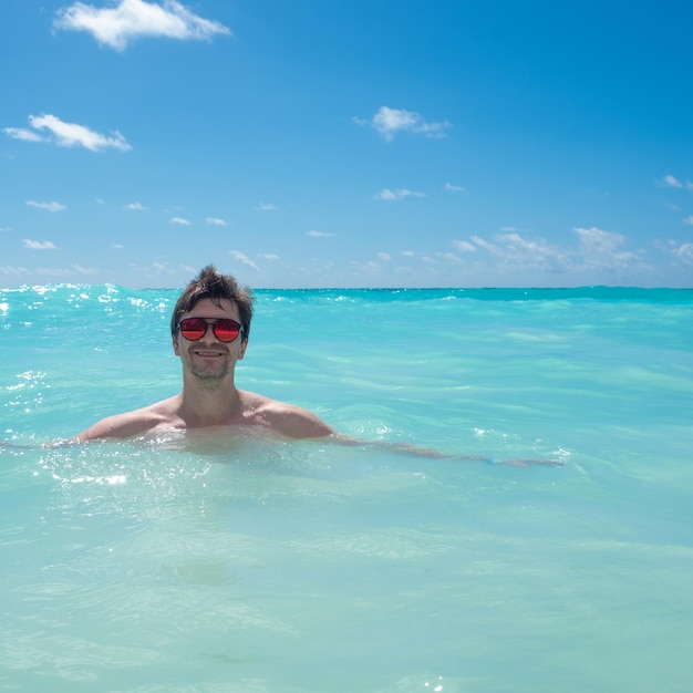 Pływanie w czystym morzu młody mężczyzna w okularach przeciwsłonecznych pływający w Morzu Karaibskim