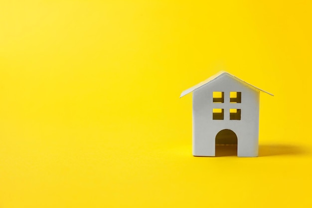 Po prostu zaprojektuj z miniaturowym białym domem zabawek na białym tle na żółtym kolorowym modnym tle nowoczesnej mody Ubezpieczenie hipoteczne wymarzony dom koncepcja Kopiuj miejsce